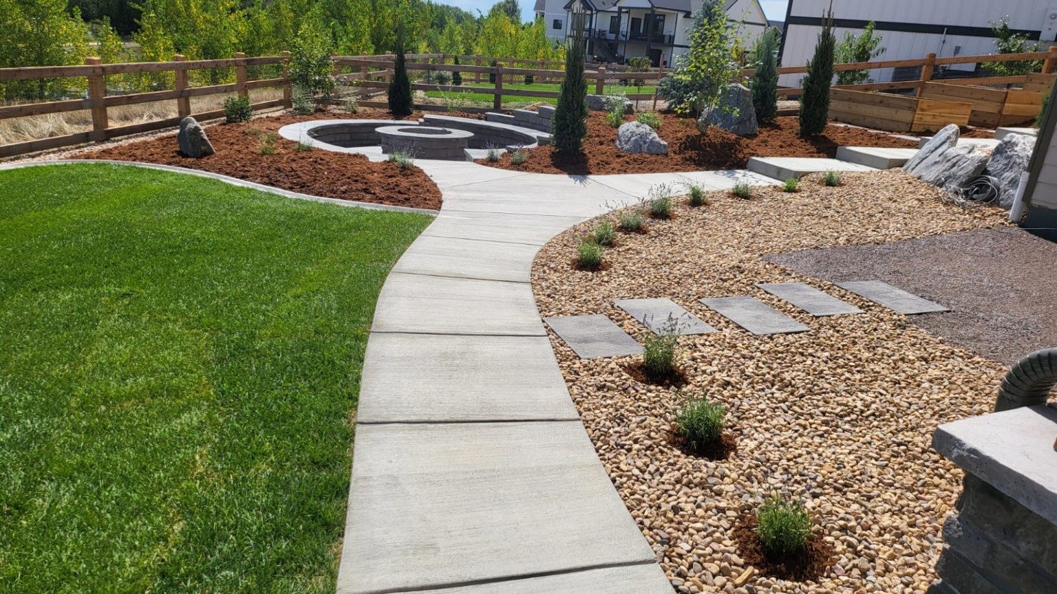 Completed landscape transformation with lawn, concrete walkway, rock beds and planting areas