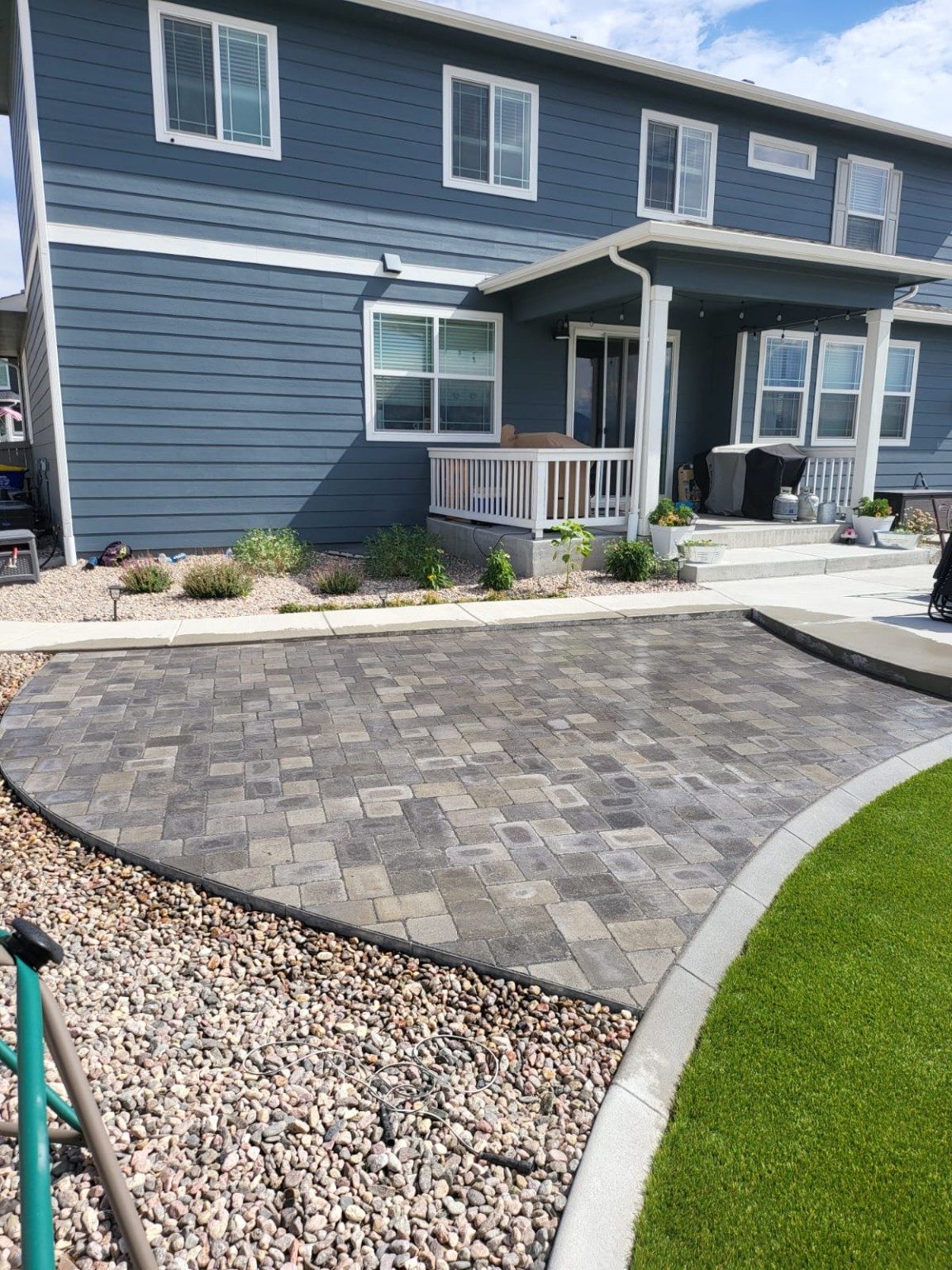 Completed paver patio and hardscape installation beside a home