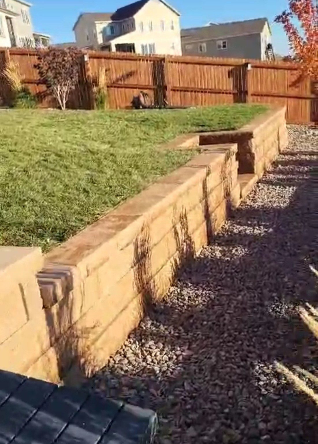 Completed block retaining wall beside a landscaped lawn